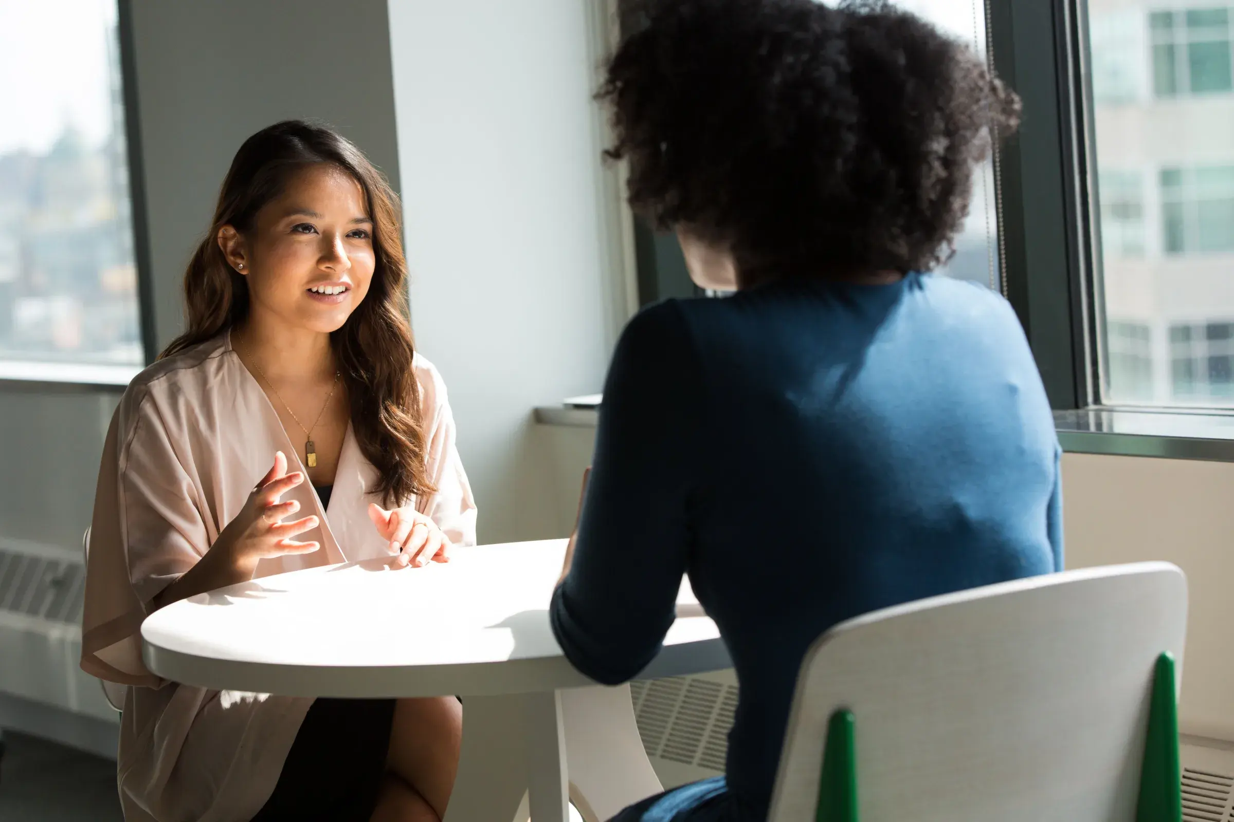 Two colleagues discussing work across a table in a bright office