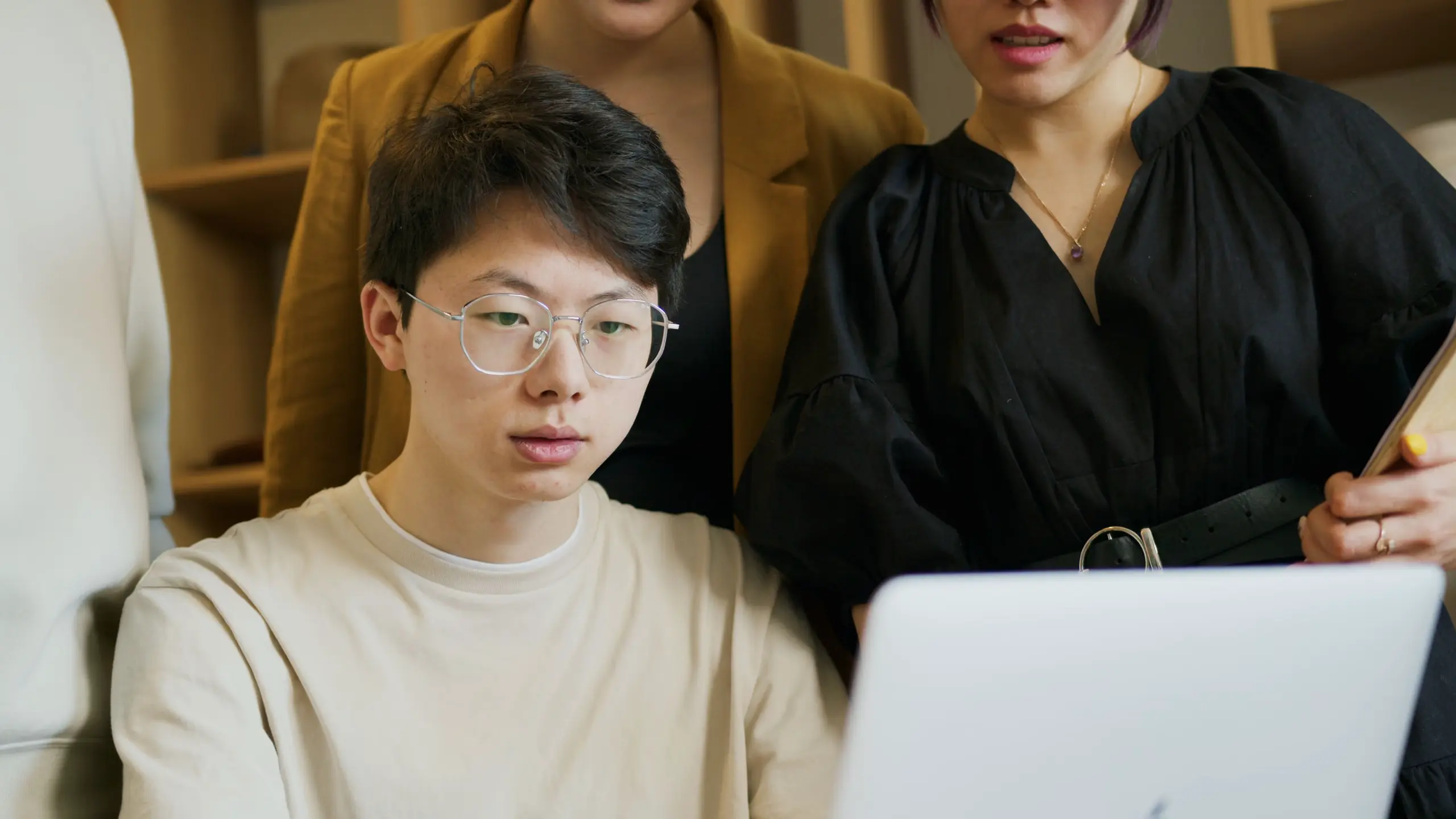 Three colleagues collaborating around a laptop